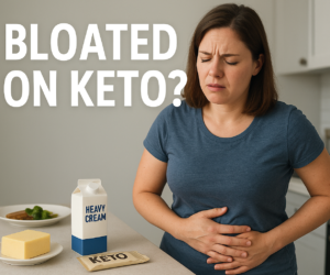 Person in a kitchen holding their stomach with frustrated bloated discomfort near keto packaged foods and dairy, beside bold text Bloated on Keto?