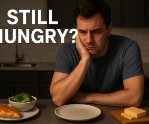 Frustrated person staring at an empty plate on a kitchen counter with bold text still hungry