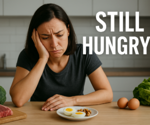 Hungry frustrated person in a kitchen staring at an almost empty plate with bold text Still Hungry on Keto